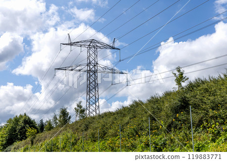 Electricity concept. Electricity concept. High voltage power line pylons, electrical tower on a green field with blue sky. 119883771