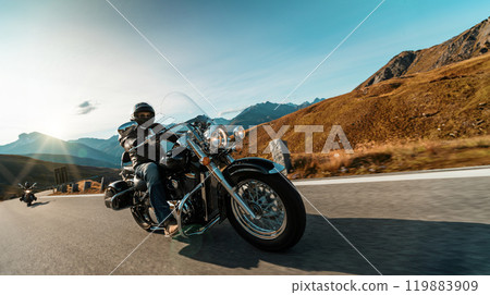 Motorbiker riding in Italian Alps during sunrise, dramatic sky. Travel and freedom, outdoor activities Motorbiker riding in Italian Alps during sunrise, dramatic sky. Travel and freedom, outdoor activities 119883909