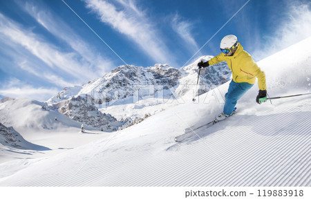 Skier skiing down a freshly groomed slope , beautiful panorama of high mountains during sunny day Skier skiing down a freshly groomed slope , beautiful panorama of high mountains during sunny day 119883918
