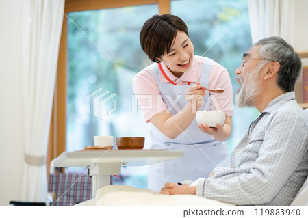 A female caregiver feeding a senior man Elderly care A female caregiver feeding a senior man Elderly care 119883940