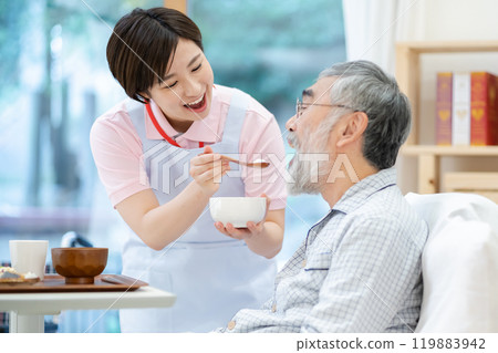 A female caregiver feeding a senior man Elderly care A female caregiver feeding a senior man Elderly care 119883942