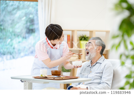A female caregiver feeding a senior man Elderly care 119883946