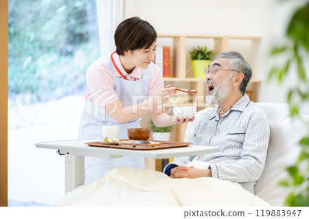 A female caregiver feeding a senior man Elderly care 119883947