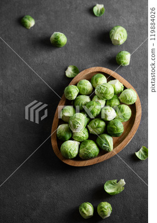 Fresh raw brussels sprouts in a wooden plate on a dark background. Fresh raw brussels sprouts in a wooden plate on a dark background. 119884026