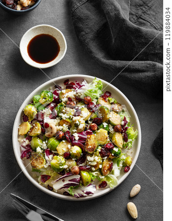 Salad of roasted brussels sprouts with lettuce, quinoa, nuts and cranberries in a plate 119884034