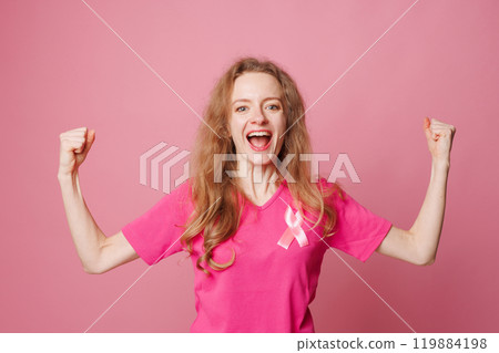 Happy young woman with pink ribbon on pink background. Breast cancer awareness concept, victory over cancer disease 119884198