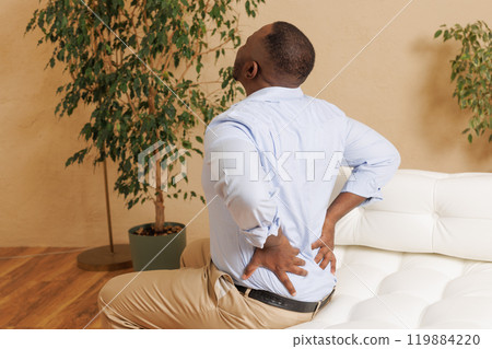 Young man suffers from back pain in the bedroom, Osteochondrosis of the lumbar region, emergency care, Young man suffers from back pain in the bedroom, Osteochondrosis of the lumbar region, emergency care, 119884220