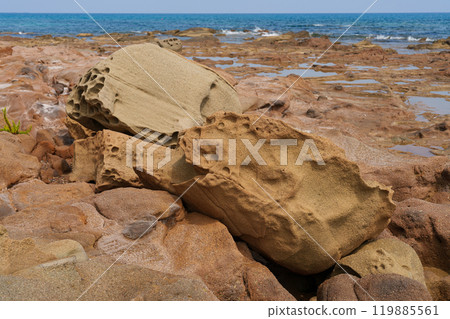 Weathered Rocks on Coastal Terrain with Sea in Background 119885561