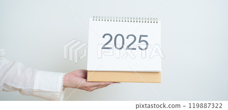Business woman hand holding and change 2025 Year Calendar on white background table in office. countdown, Happy New Year, Resolution, Year End and New Start and Goals Plan Action Concept 119887322