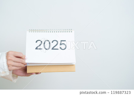 Business woman hand holding and change 2025 Year Calendar on white background table in office. countdown, Happy New Year, Resolution, Year End and New Start and Goals Plan Action Concept 119887323