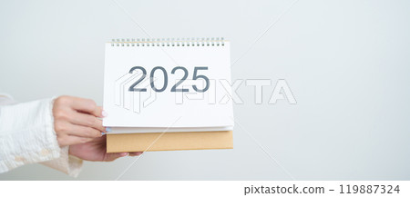 Business woman hand holding and change 2025 Year Calendar on white background table in office. countdown, Happy New Year, Resolution, Year End and New Start and Goals Plan Action Concept 119887324