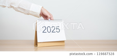 Business woman hand change 2025 Year Calendar on table in office background. countdown, Happy New Year, Resolution, Year End and New Start and Goals Plan Action Concept Business woman hand change 2025 Year Calendar on table in office background. countdown, Happy New Year, Resolution, Year End and New Start and Goals Plan Action Concept 119887328