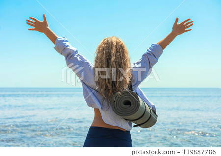 Happy yoga woman celebrate win with raising hands at sunny sea sky back view closeup 119887786