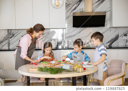 Happy family mother and children in aprons making Christmas cookies together while cooking  119887825