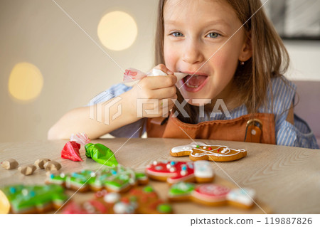 A little girl decorates a Christmas gingerbread mitten. Concept of preparations for Christmas A little girl decorates a Christmas gingerbread mitten. Concept of preparations for Christmas 119887826