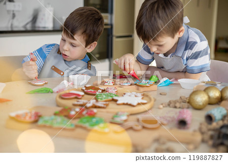 Happy family mother and children in aprons making Christmas cookies together while cooking Happy family mother and children in aprons making Christmas cookies together while cooking 119887827
