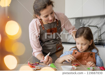 Happy family mother and daughter in aprons making Christmas cookies together while cooking Happy family mother and daughter in aprons making Christmas cookies together while cooking 119887830