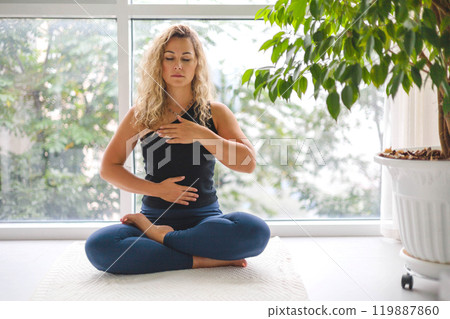 Woman yoga meditation sitting in lotus position near panorama window with houseplant at home Woman yoga meditation sitting in lotus position near panorama window with houseplant at home 119887860