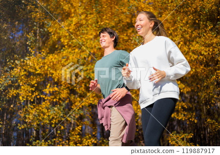 Young beautiful couple jogging in city beautiful autumn park and forest, enjoying outdoor sports 119887917