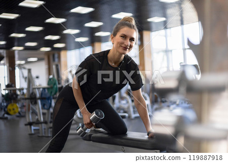 Strong beautiful fitness woman training back doing exercise with dumbbells at gym 119887918