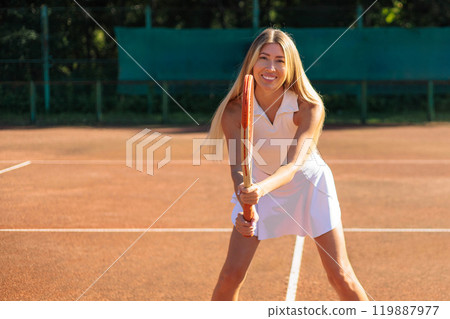 Woman tennis player in white clothes waiting ball holding rocket at summer outdoor court Woman tennis player in white clothes waiting ball holding rocket at summer outdoor court 119887977