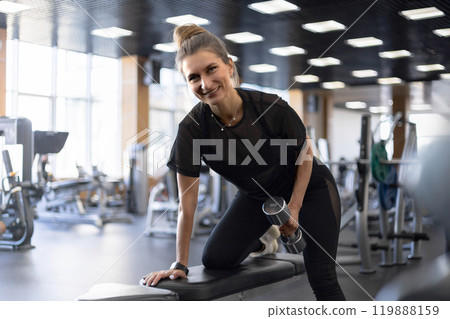 Strong beautiful fitness woman training back doing exercise with dumbbells at gym 119888159