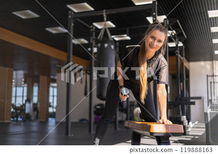 Strong beautiful fitness woman training back doing exercise with dumbbells at gym 119888163