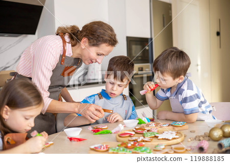 Happy family mother and children in aprons making Christmas cookies together while cooking 119888185