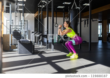 Fitness woman making squat with rubber band training butts at sportive gym 119888187