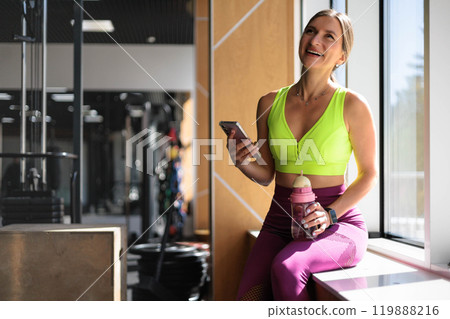 Fitness woman relaxing on mat use smartphone chatting at gym enjoy break 119888216