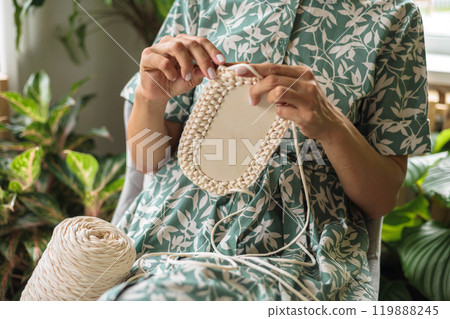 Women's hands crochet a storage basket from white and beige yarn. Women's hands crochet a storage basket from white and beige yarn. 119888245
