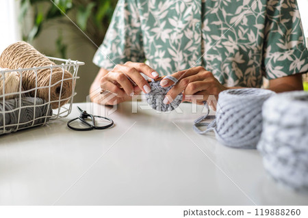 Close up female hands. Girl crochets from gray cotton yarn. Skeins of natural, natural colors Close up female hands. Girl crochets from gray cotton yarn. Skeins of natural, natural colors 119888260