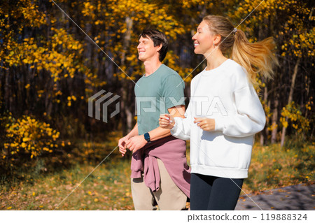 Young beautiful couple jogging in city beautiful autumn park and forest, enjoying outdoor sports.  119888324