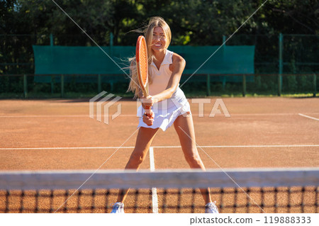 Woman tennis player in white clothes waiting ball holding rocket at summer outdoor court Woman tennis player in white clothes waiting ball holding rocket at summer outdoor court 119888333