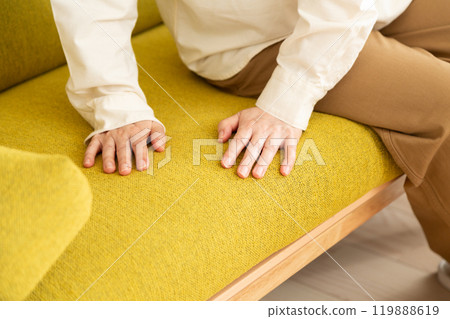 A middle-aged to senior woman checking the comfort of her sofa at home 119888619