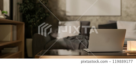 A close-up of a laptop on a coffee table in a contemporary grey living room at night. 119889177