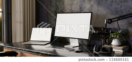 A modern loft podcaster office workspace featuring multiple screens from a laptop and a computer. 119889181