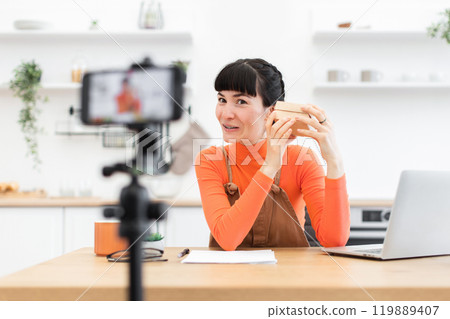Caucasian female blogger filming unboxing video in modern kitchen 119889407