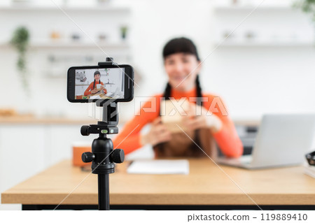 Caucasian female blogger recording online unboxing video in modern kitchen Caucasian female blogger recording online unboxing video in modern kitchen 119889410