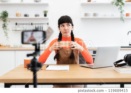 Caucasian female blogger filming content at home with laptop and coffee 119889415