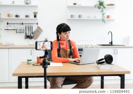 Young woman working remotely from modern kitchen workspace 119889491