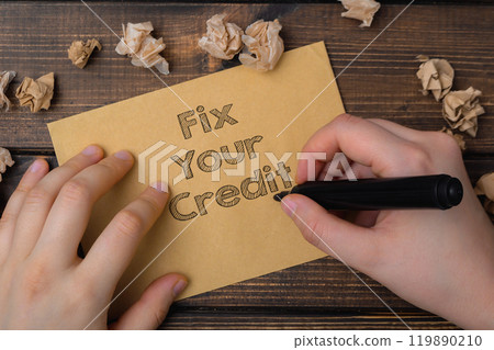 A person is writing on a piece of paper that says Fix Your Credit A person is writing on a piece of paper that says Fix Your Credit 119890210