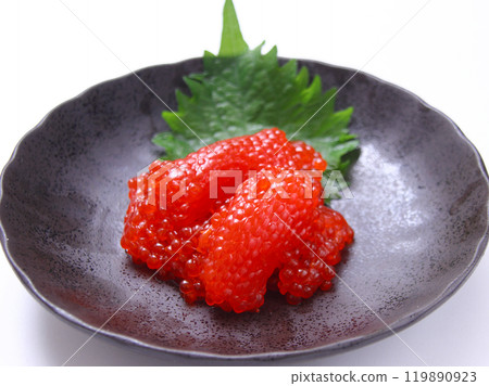 Cut salmon roe marinated in soy sauce on a round plate with a wood grain background 119890923