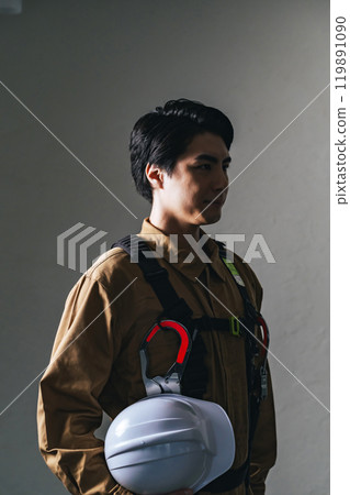 Male worker wearing work clothes and holding a helmet Male worker wearing work clothes and holding a helmet 119891090