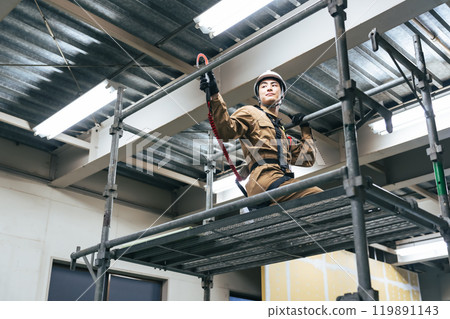 Workers climbing up scaffolding at a construction site to work at height 119891143