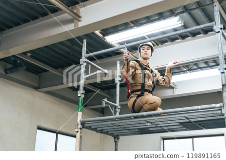 Workers climbing up scaffolding at a construction site to work at height 119891165