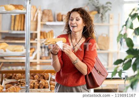 Cheerful woman holding just cooked bocadillo while standing in bakehouse 119891167