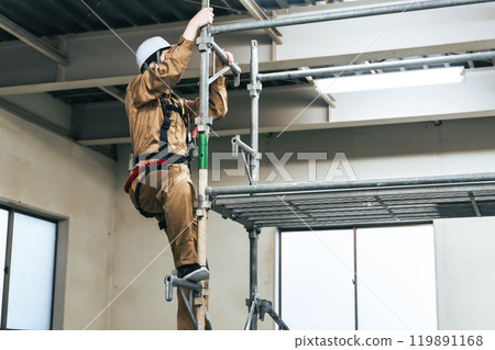 Workers climbing on scaffolding at a construction site 119891168