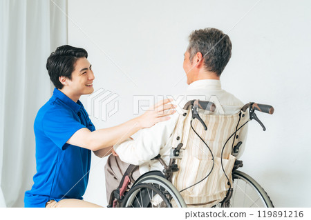 Care staff supporting a senior man in a wheelchair 119891216
