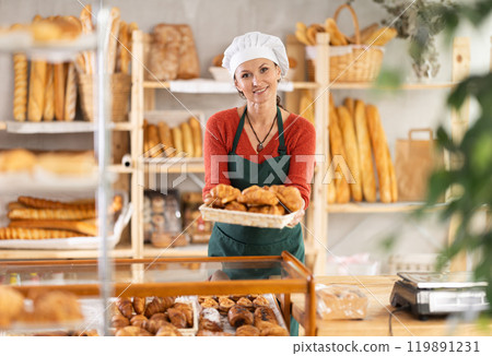 Portrait of positive woman bakery worker with croissants 119891231